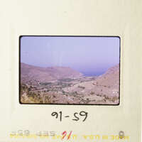 A scenic view of a mountainous landscape with a clear sky and a small town visible in the distance.