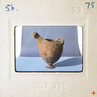 An old, cracked clay pot sitting on a blue surface.