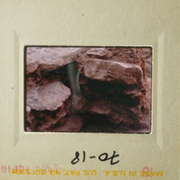 Photo of rock formation with red clay-like substance, possibly taken with an old camera.