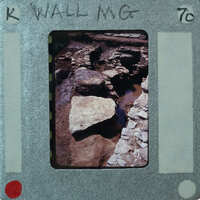 A photograph of a rocky wall, placed inside an old film strip container with handwritten notes on it.