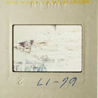 A photograph with a yellowed appearance, featuring a faded and blurry scene, possibly of a natural landscape or a building facade, with a blue handwritten note on the bottom left corner.