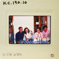 A vintage photo of people gathered around a table with food and drinks. Catalog number KC.190.10