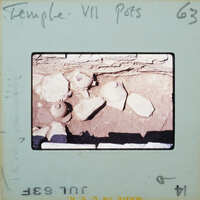 Pottery in situ on surface in stone walled room.