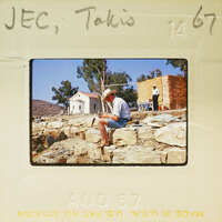 Man sitting on rocks, reading a book.