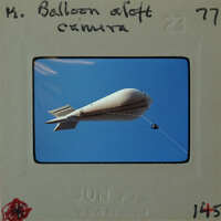 A vintage photograph of a hot air balloon flying against a clear sky.