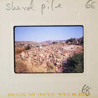 A pile of rocks on a hillside with mountains in the background.