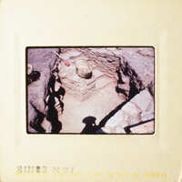 The photo shows an archaeological site with stone ruins and artifacts, including pottery, under excavation.