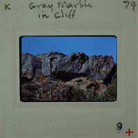 A vintage film strip with a photograph of rocky cliffs and greenery.