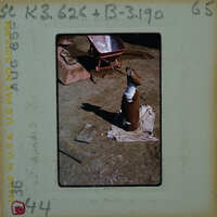 A photograph of a work area with various tools and materials, including a large pipe on the ground.