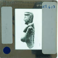 Clay figurine from the side, displayed with a white background and a label.