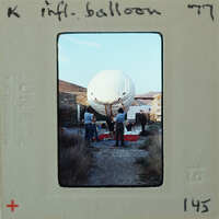 A vintage photograph of people preparing a large white balloon.