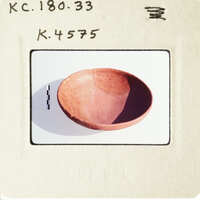 A small, light brown clay pot with a handle on top.