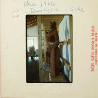 Wooden sculpture on display inside a building with exposed wooden beams and artwork on the wall.