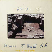 This is an old photograph showing ruins with stone structures and some vegetation.