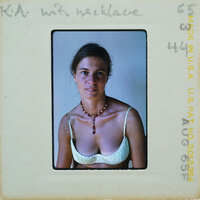 Woman wearing a necklace and tank top, smiling at the camera.