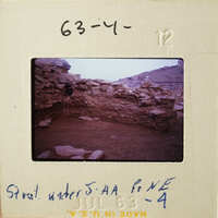 A photograph of an ancient stone structure with a view of mountains in the background.