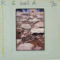 A photograph of a stone structure, possibly ruins or an old building, with visible decay and vegetation growth.