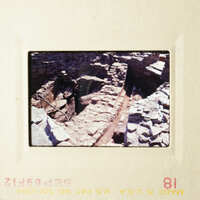 The photograph shows an ancient stone structure, possibly a tunnel or cave, with visible rock walls and a narrow passageway.