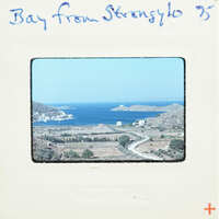 A vintage photograph of a coastal landscape with blue waters and mountains, labeled "Bay from Strongylos".