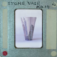 A photograph of a stone vase with a label on it.