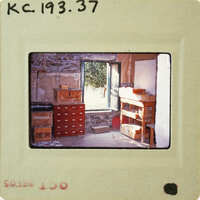 A photograph of a cluttered room with shelves and boxes, taken from an old film negative.