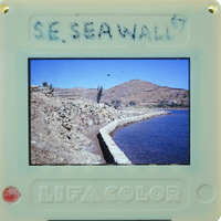 A seawall with mountains and water in the background.