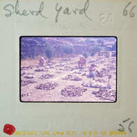 A vintage photograph of a person working on an archaeological site with stone ruins and ancient artifacts.