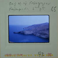 A photograph of a rocky coastline with the ocean and sky visible, on a film strip labeled "Bay N. of Ios".