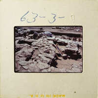 Ancient ruins with stone walls and dirt ground, possibly from an archaeological site.