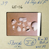 The image shows a collection of broken pottery pieces on a table.