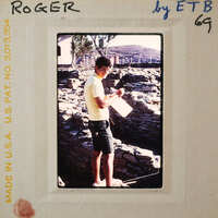 Man standing in front of a stone wall with a clipboard and pen, possibly conducting an inspection or survey.