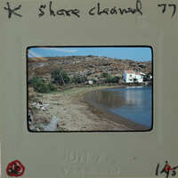 Photograph of a beach with a house and mountains.