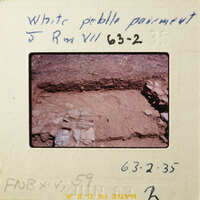 A photograph of an archaeological site with exposed layers and stones.