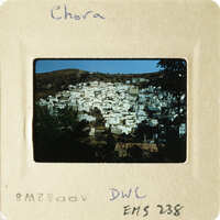 A photograph of a mountainous village with houses and trees, taken during daylight hours.