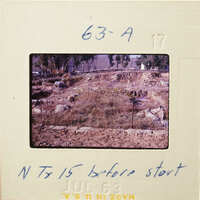 This is an old photograph showing a dirt area with trees and shrubs, possibly taken before construction started.