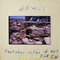 Stone ruins with vegetation on hillside.