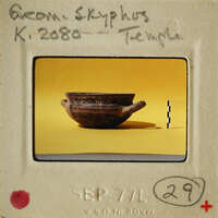 Ancient Greek vase on display with a yellow background and white border.