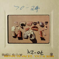 The photo shows an array of broken pottery pieces on a table, including shards and fragments.