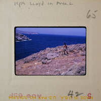 A photo of a person standing on a cliff overlooking the ocean with a vintage look.