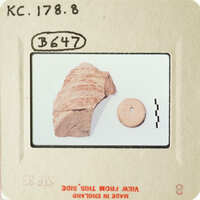 Ancient artifact on a white surface, with a smaller object beside it.