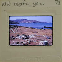 An old photo of a coastal archaeological site with ruins and the sea in the background, framed by an aged film strip.