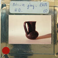 Photo of a black clay vase with handwritten label on a card.