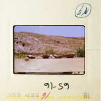 A vintage photo of an outdoor scene with a wooden table and three bowls on it.