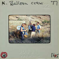 A group of people standing outdoors, possibly a balloon crew preparing equipment.