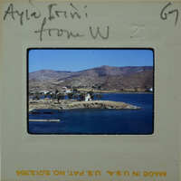 A vintage photograph of a scenic island with mountains and water, encased in an old film strip container.