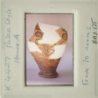 A damaged clay pot with intricate designs on display.