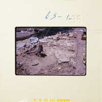 A photograph of an archaeological site with exposed stone ruins and excavation tools.