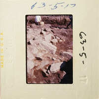 Old photograph of an archaeological site with excavated stone ruins and people working on-site.