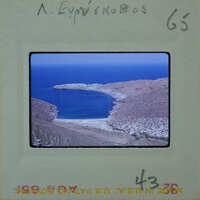 A photograph of a serene coastal landscape with clear blue water and rocky hillsides.