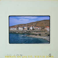 A photograph of a seaside village with abandoned houses and boats on the shore.